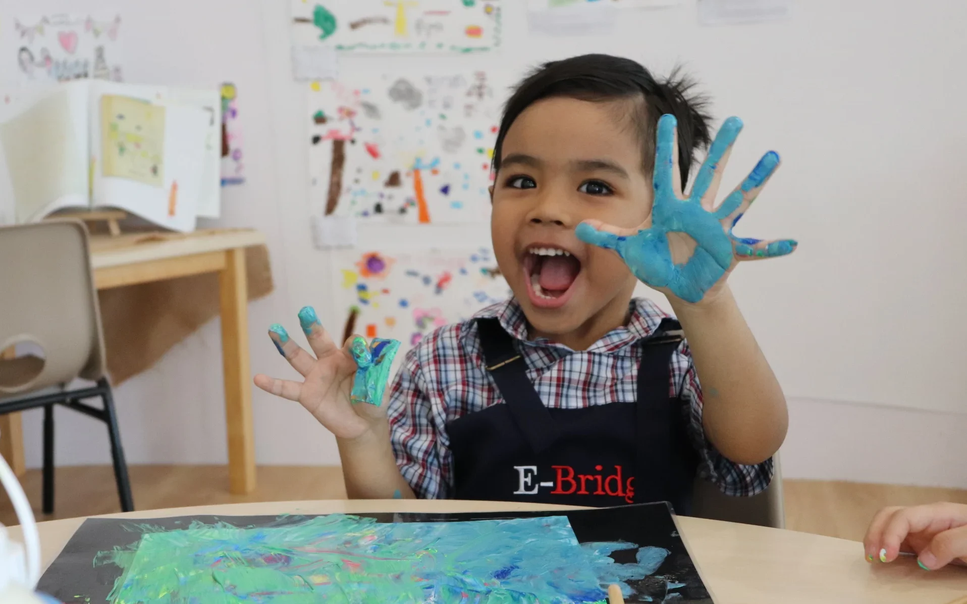 Happy child with painted hands in preschool art class