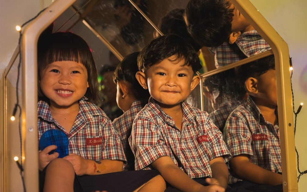 Preschool children smiling in school uniforms during playtime activity