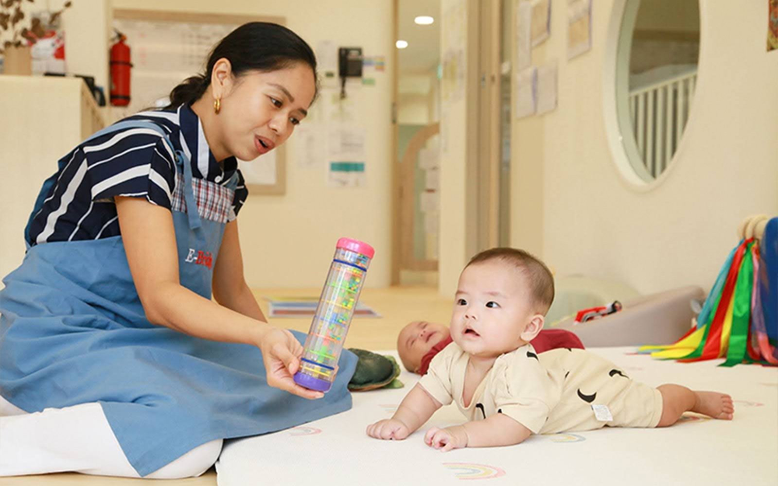 E-Bridge teacher engaging baby with a sensory toy