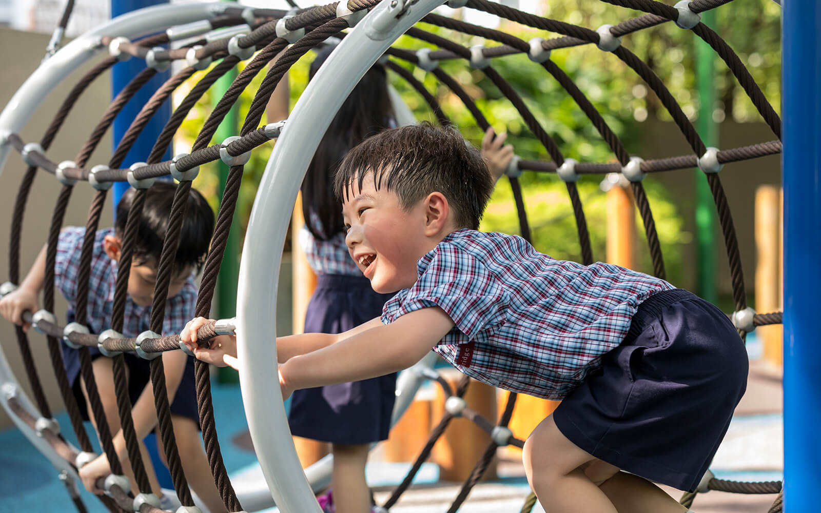 Happy children playing in an e-bridge preschool playground tunnel