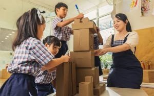 Teacher and students building a tower with cardboard boxes.