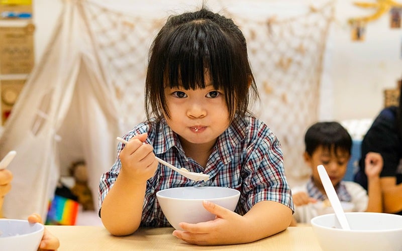 Toddler practicing healthy eating with a balanced home meal.